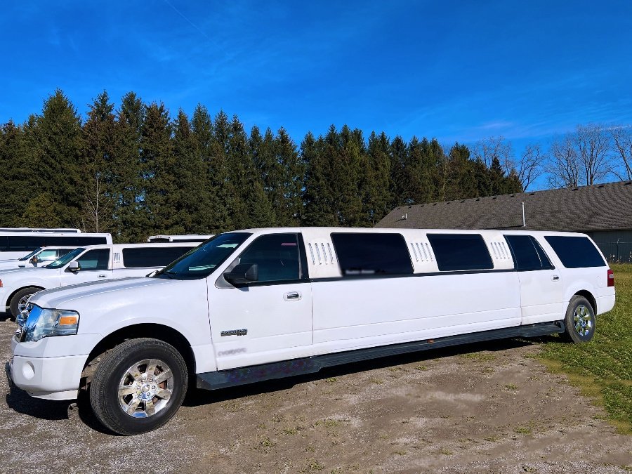 White stretch SUV limousine parked outdoors under a clear blue sky.