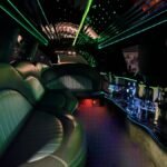 Green LED-lit interior of black SUV limo with luxury leather seating and star ceiling.