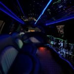Blue and green illuminated interior of black SUV limo with star ceiling and bar.