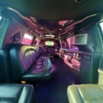 Wide-angle view of SUV limo interior with leather seats and glossy ceiling panels.