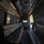 Daylight interior of 15-passenger party bus with black leather bench seating – Brantford Limo.