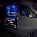 Night exterior of 15-passenger Mercedes party van with door open and LED lights glowing – Brantford Limo.