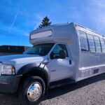 Front side angle of white 25-passenger limo bus parked outdoors – Brantford Limo.