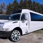 Front angle of white 30-passenger party bus showing tinted windows and chrome accents – Brantford Limo.