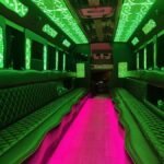 Party bus interior glowing with green ceiling lights and pink LED floor – Brantford Limo.