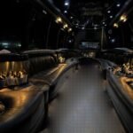Dimly lit interior of 30-passenger party bus with cup holders, curved leather seats, and LED lights – Brantford Limo.