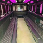 Pink-lit party bus interior with diamond-stitched leather seating – Brantford Limo.