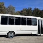 Side view of 30-passenger white party bus parked near forest – Brantford Limo.