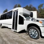 Angled front view of large white 30-passenger party bus with tinted windows – Brantford Limo.