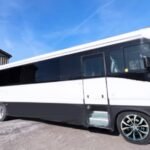 White and black 38-passenger party bus parked outside under blue sky – Brantford Limo.
