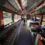 Daytime view inside 38-passenger party bus with leather seating, tables, and chrome ceiling – Brantford Limo.
