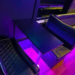 Close-up of party bus table seating with quilted leather chairs and ambient purple lighting – Brantford Limousine.